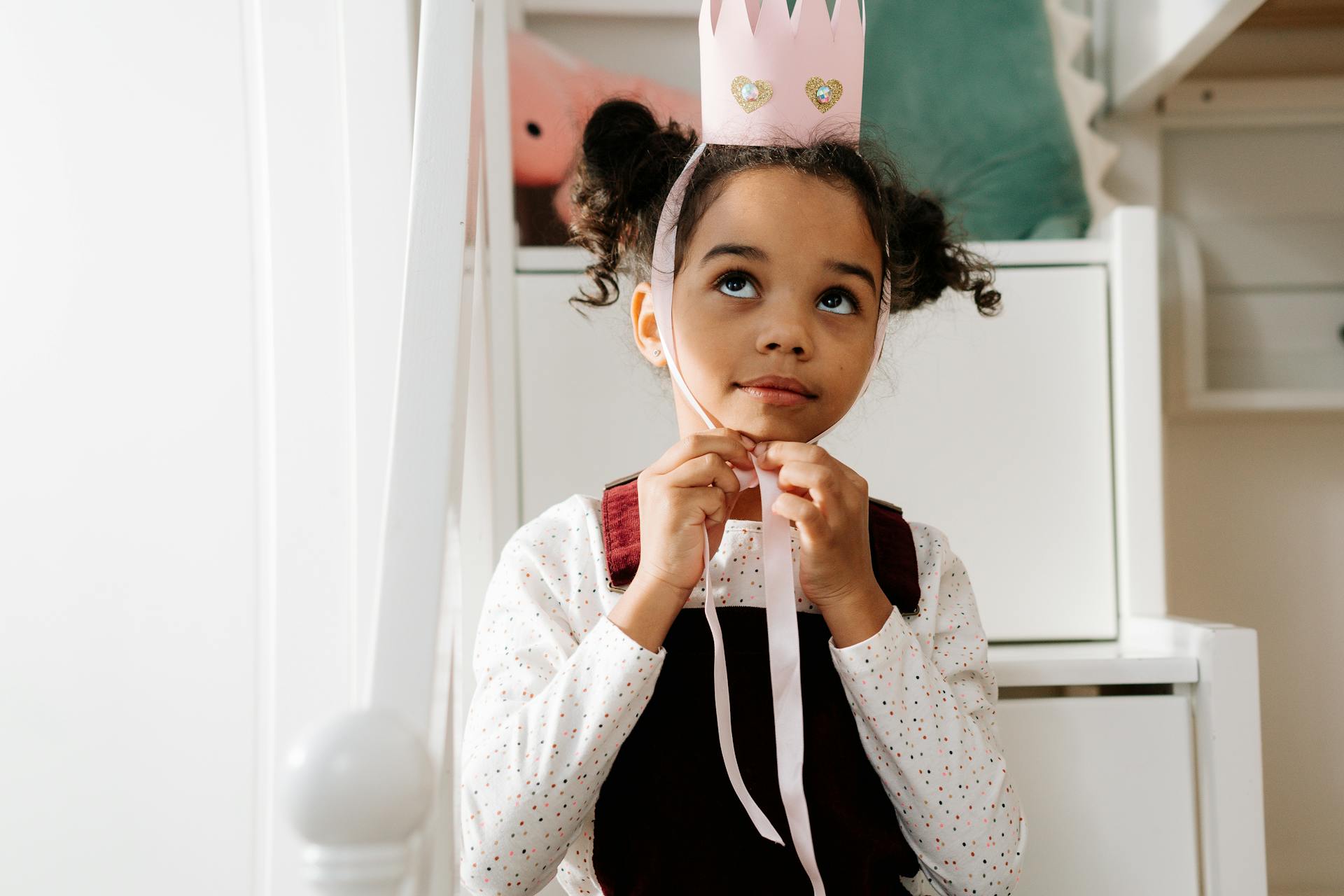 Adorable child wearing a handmade princess crown, enjoying dress-up indoors.