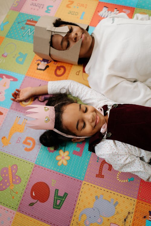 Free Girl in White Long Sleeve Shirt Lying on Puzzle Mat Stock Photo