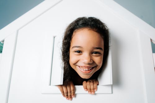 Smiling Girl Sticking her Head Out of a Playhouse Window