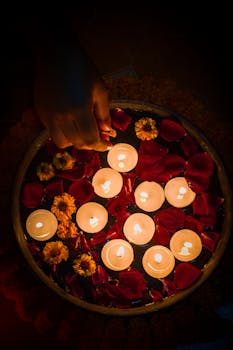 Overhead view of glowing candles floating among petals and flowers, creating a serene ambiance.