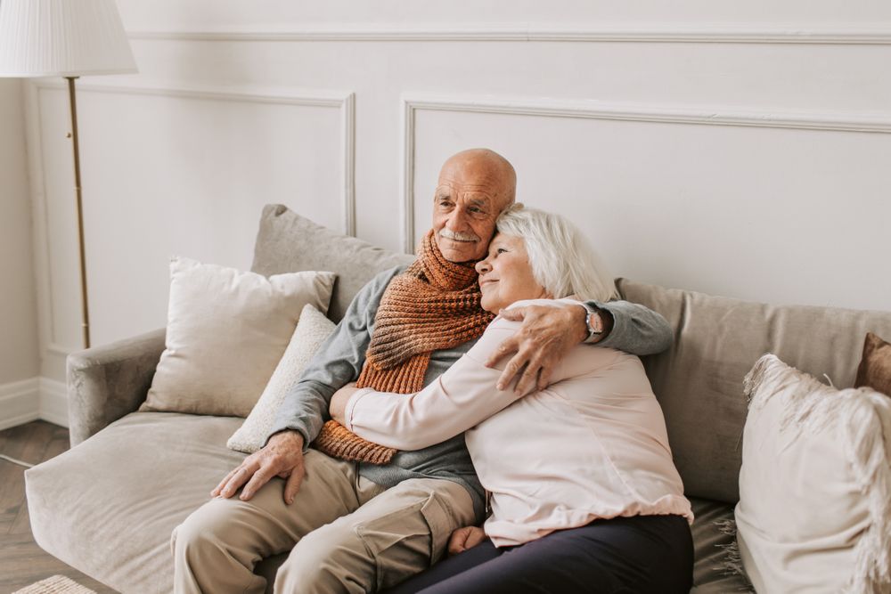 A smiling senior couple sitting together on a sofa at home