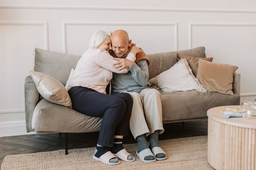 Free Tender moment of affection between a senior couple embracing on a comfortable couch indoors. Stock Photo