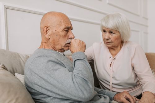 Free An elderly couple sitting on a couch, showing care and affection indoors. Stock Photo