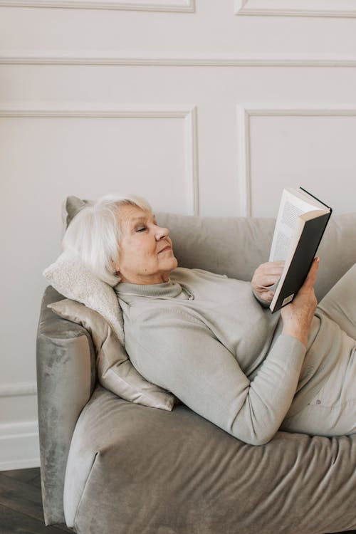 Free A Woman on a Couch Reading a Book Stock Photo