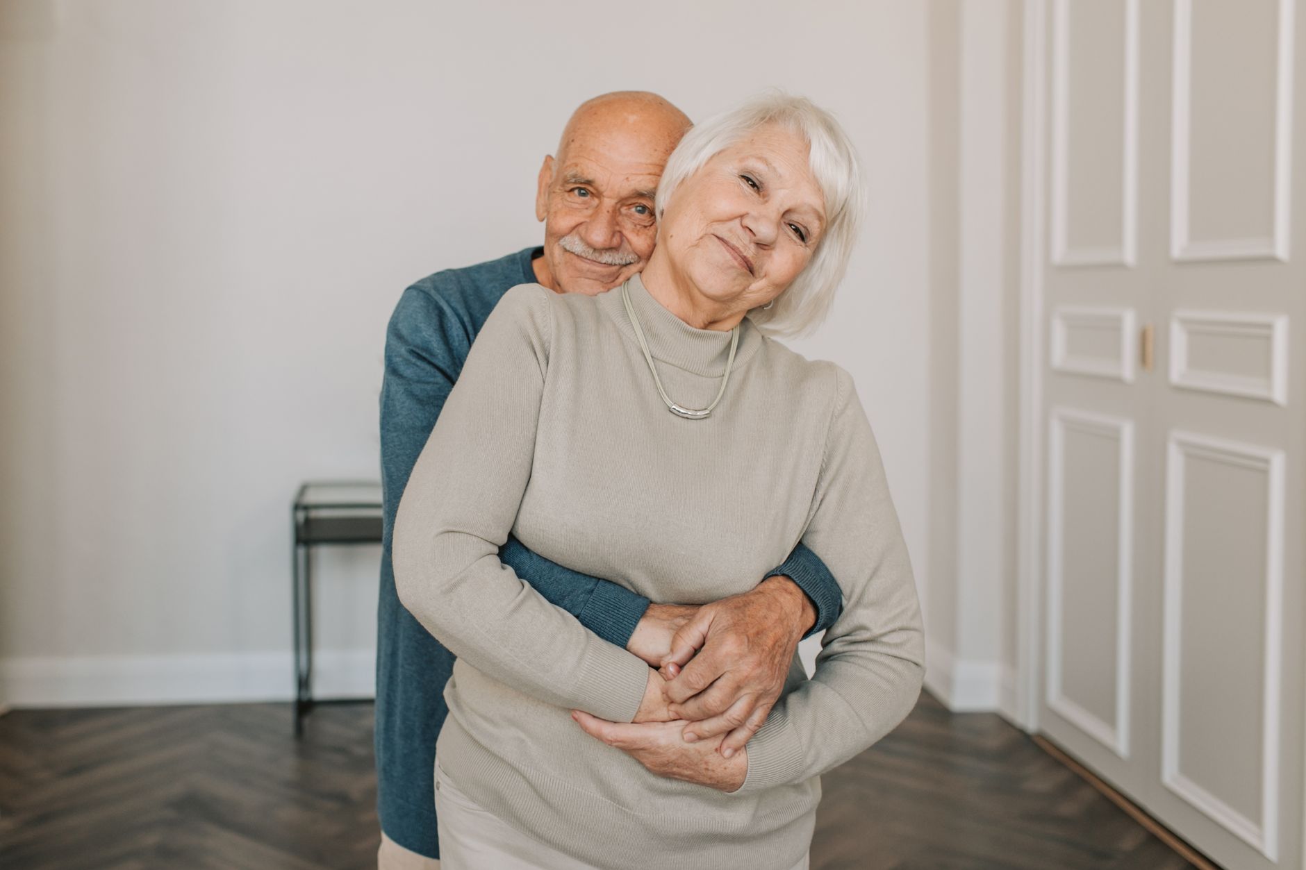 Heartwarming portrait of an elderly couple embracing happily indoors, showcasing love and companionship.