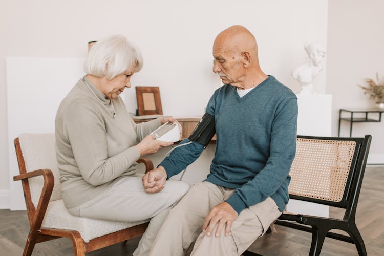 Woman Taking The Blood Pressure Of A Man In Blue Sweater