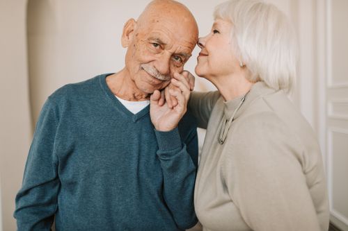 Free A heartwarming portrait of a senior couple expressing affection indoors, symbolizing love and happiness. Stock Photo