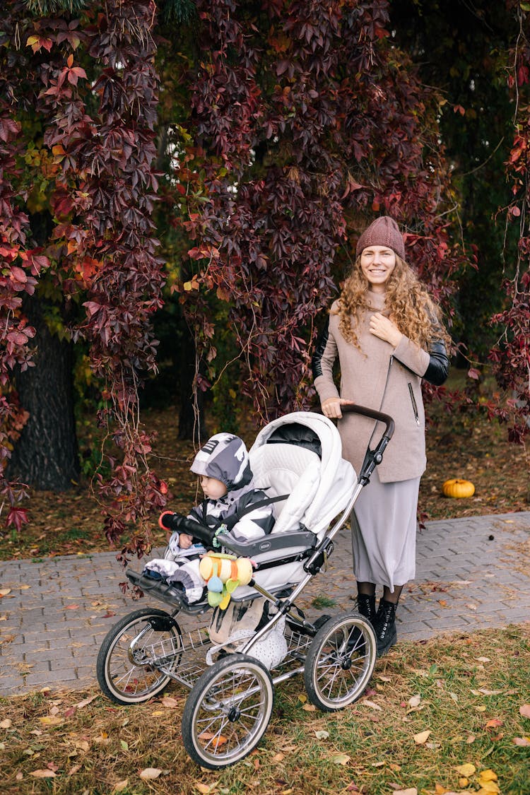 Smiling Woman Pushing A Stroller With A Baby