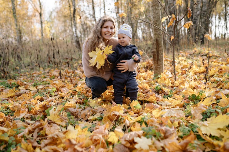 Mother And Child Sitting On Dried Leaves