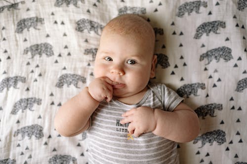 Free Baby in White and Black Stripe Onesie Lying on White and Black Textile Stock Photo