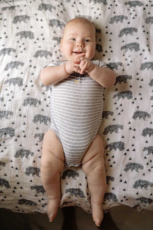 Free Baby in White and Gray Stripe Onesie Lying on White and Black Animal Print Textile Stock Photo