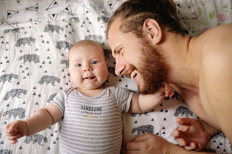 Shirtless Man Beside Baby In White And Gray Stripe Onesie Sleeping