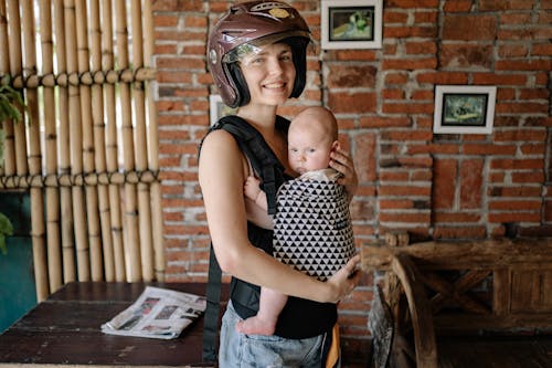 Free Woman Wearing Brown Helmet While Carrying Her Baby  Stock Photo