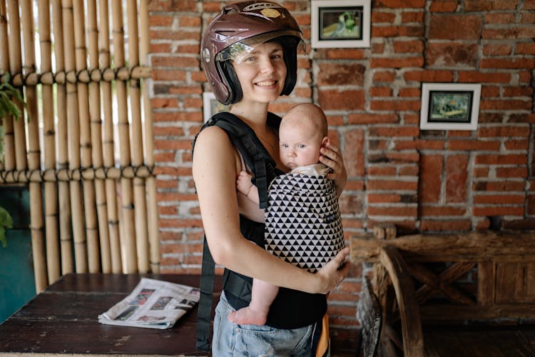 Woman Wearing Brown Helmet While Carrying Her Baby 