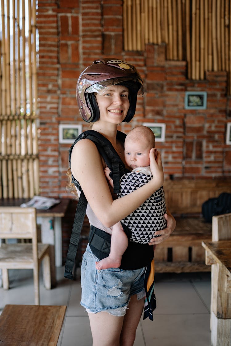 Woman Wearing Brown Helmet While Carrying Her Baby