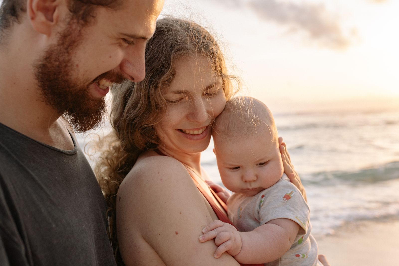 Happy family holding a baby at golden hour