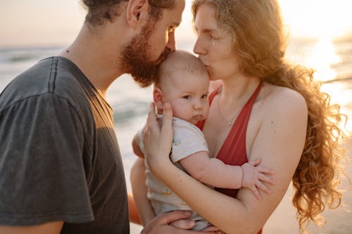 Man and Woman Kissing their Child