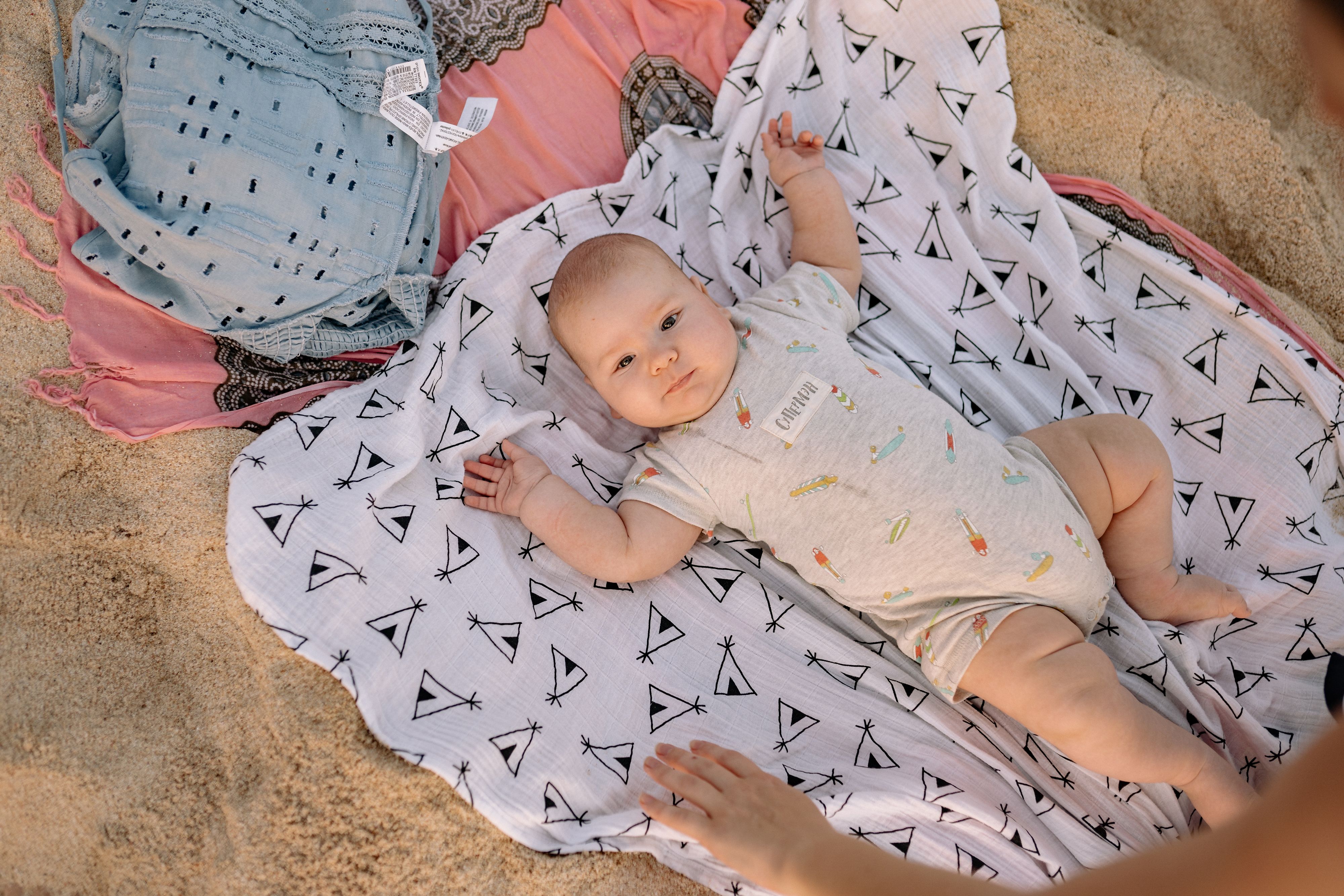 Bébé allongé sur une couverture à l’ombre au bord de la plage