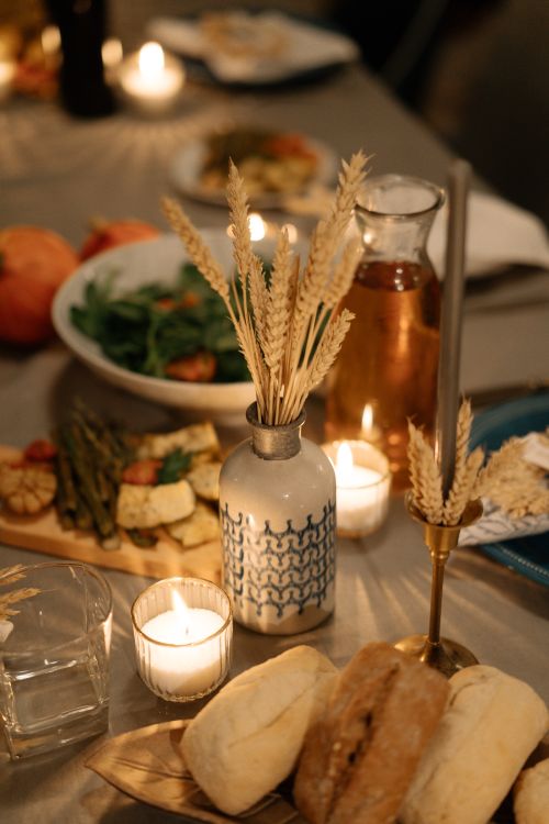 Free Warm and inviting holiday dinner table setting with candles, bread, and autumn decor. Stock Photo