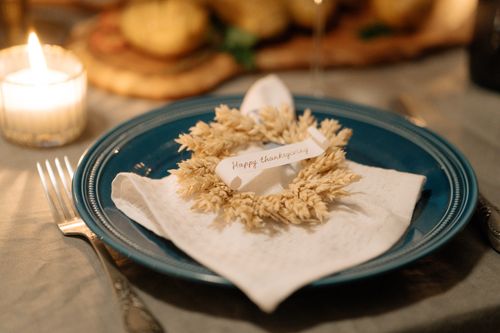 Free A cozy Thanksgiving table setting featuring a wreath napkin and candlelit ambiance. Stock Photo