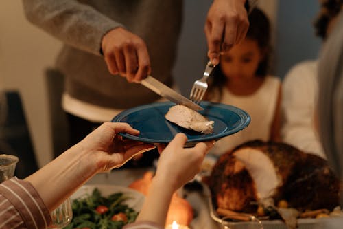 Person Holding Fork and Knife with Meat