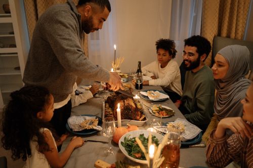 Free Warm family gathering around a festive table with turkey, celebrating a special holiday indoors. Stock Photo