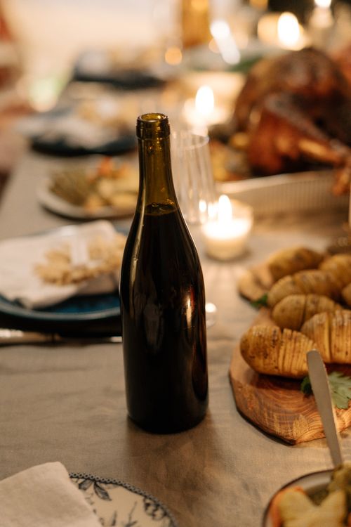 Free Cozy Thanksgiving dinner setup with wine and roast turkey, perfect for holiday gatherings. Stock Photo