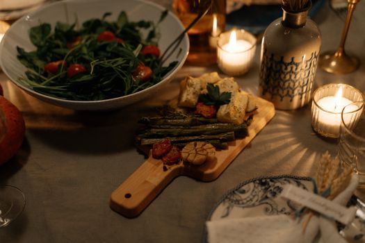 Elegant dinner setting with fresh salad and roasted vegetables in candlelight, perfect for a cozy evening.