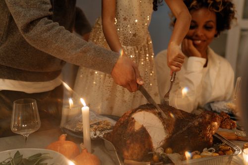 Free A family enjoys a cozy Thanksgiving dinner with a turkey centerpiece and candlelight ambiance. Stock Photo