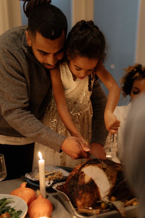 Free Father and daughter carving turkey at family Thanksgiving dinner indoors. Stock Photo