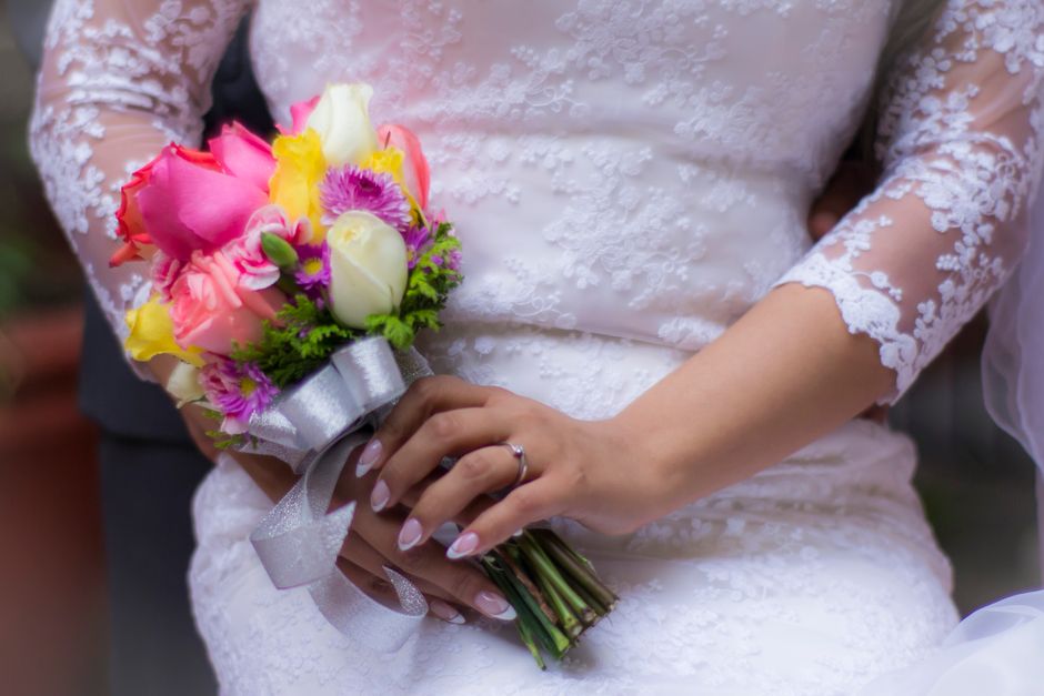 Professional services | Premier Private Rides A close-up of a bride in a lace dress holding a vibrant wedding bouquet.