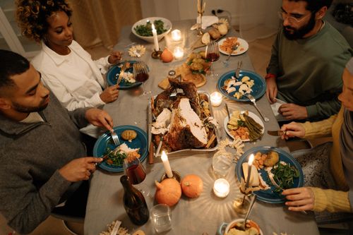 Free Warm Thanksgiving dinner scene with friends around a table enjoying a turkey feast by candlelight. Stock Photo