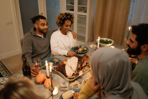 Free Friends share a joyful meal indoors, enjoying food, conversation, and candles. Stock Photo