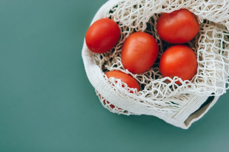 A Red Tomatoes On A Mesh Bag