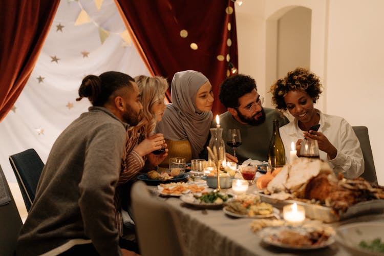 A Group Of People Looking At The Mobile Phone Holding By The Woman In White Long Sleeves