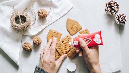 Free A Person Assembling a Gingerbread House Cookie Stock Photo