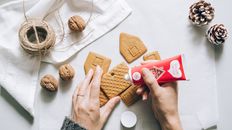 A Person Assembling a Gingerbread House Cookie