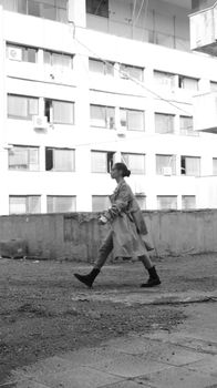 Black and white cityscape of a woman walking past a building.