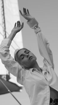 Monochrome portrait featuring a serene woman posing with eyes closed and hands raised.