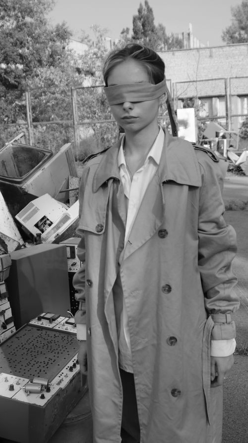 Free Artistic black and white photo of a blindfolded woman in a coat, posing amidst urban decay. Stock Photo