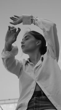 Striking grayscale portrait of a woman in a dress shirt, captured in a natural pose.