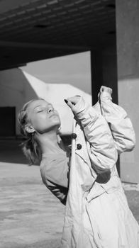 Striking black and white portrait of a woman posing outdoors with a coat in hand.