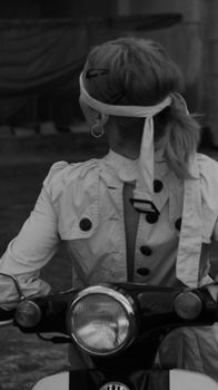 Black and white shot of a woman blindfolded on a motorcycle, back view.