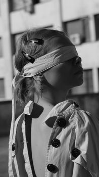 Artistic monochrome portrait of a fashionable blindfolded model with hair clips and button details.