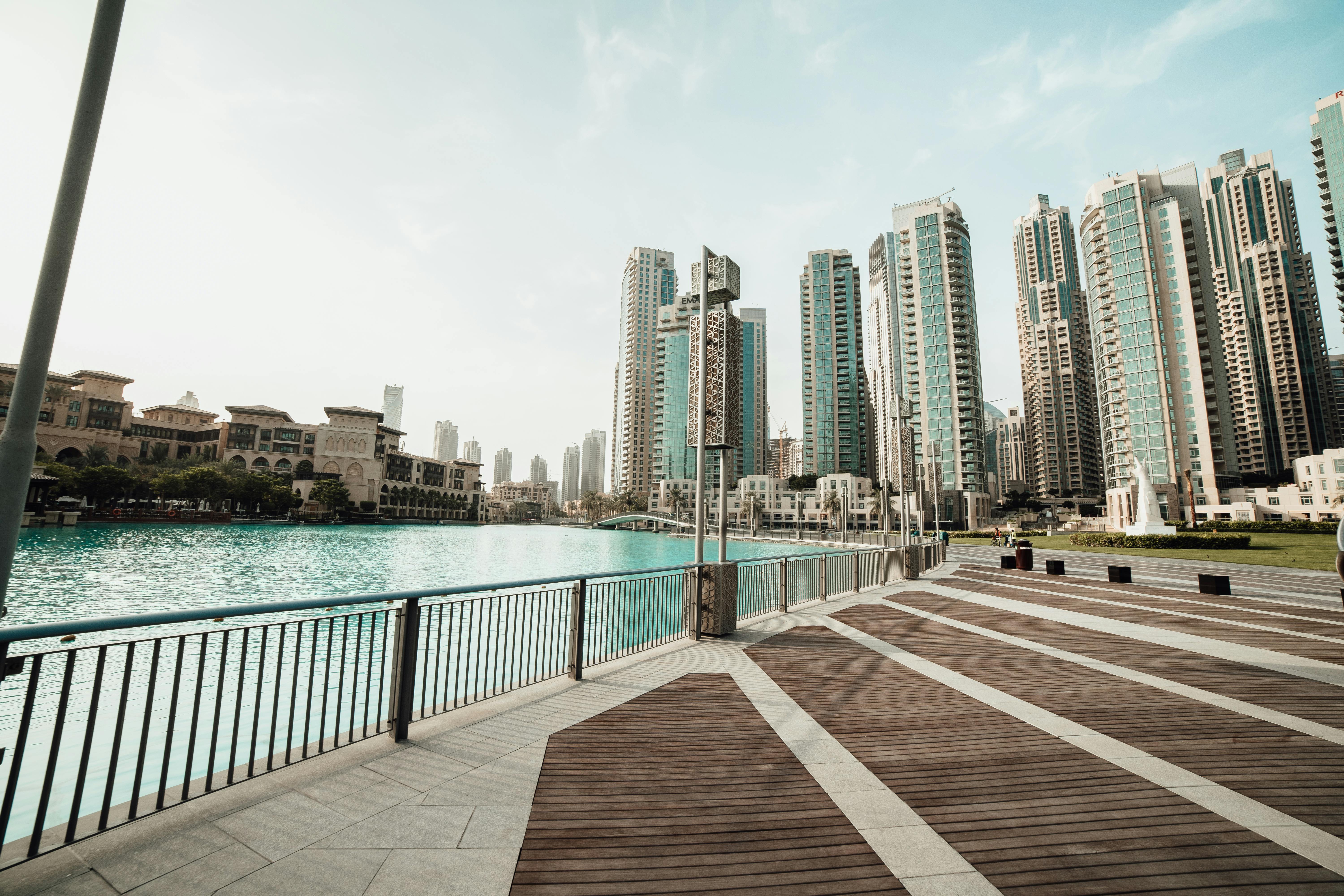 Majestic skyscrapers lining a tranquil waterfront in downtown Dubai, UAE, on a sunny day.