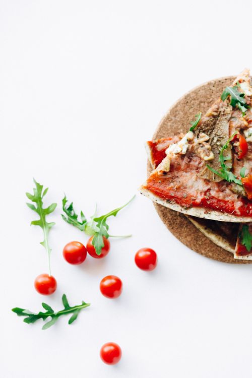 Free Close-up of Italian pizza slices garnished with arugula and cherry tomatoes on a white surface. Stock Photo