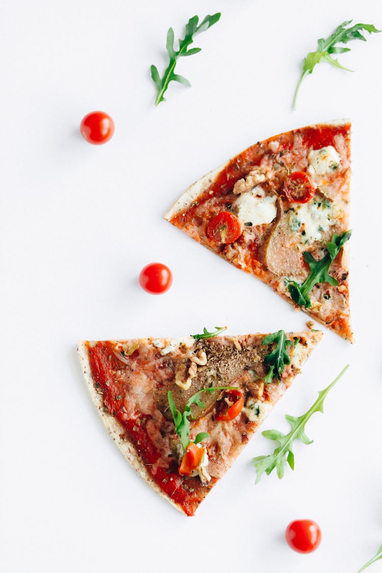 Two Slices Of Pizza With Arugula And Cherry Tomatoes