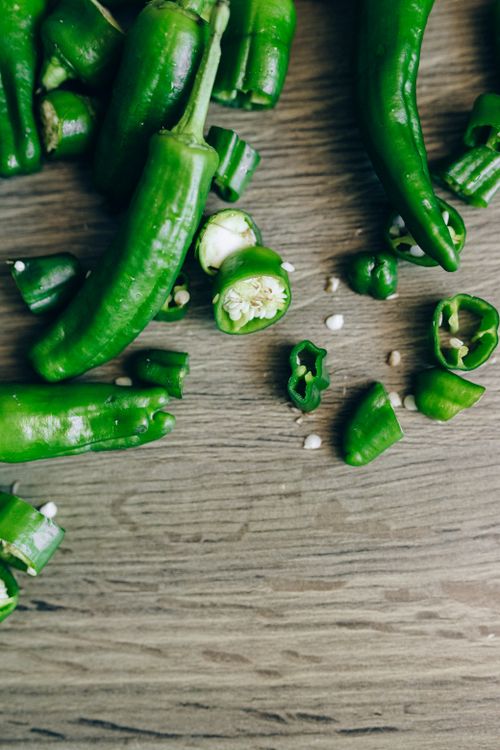 Free Sliced green chillies scattered on a wooden table, highlighting freshness and spice. Stock Photo