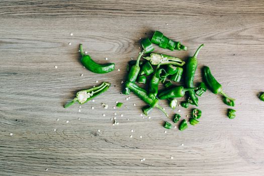 Sliced green chili peppers with seeds on a wooden surface, highlighting freshness and texture.
