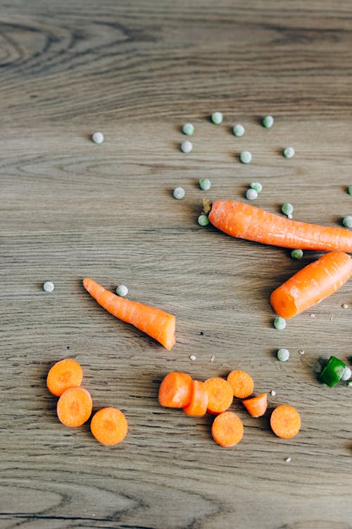 Free Sliced Carrots and Peas on Wooden Surface Stock Photo